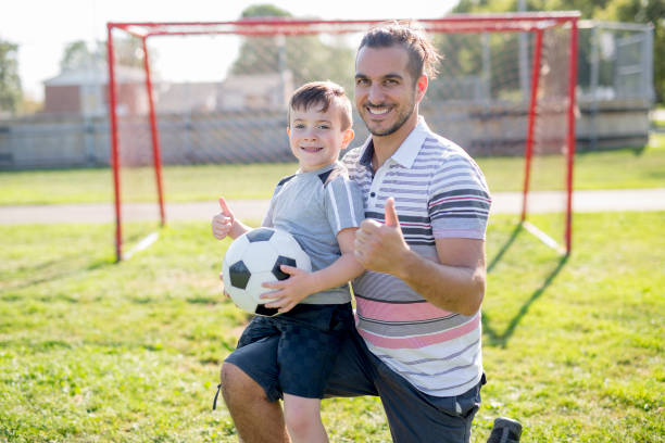 istock man with child playing football on field 854664072