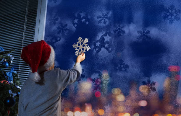 istock Little boy putting snowflake on the window 854683940