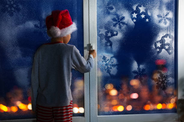 istock Boy before Christmas near window with snowflakes 854686798