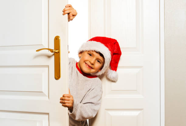 istock Boy looking out from the white door in Santa hat 854686932