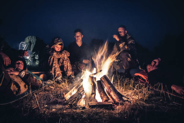 gruppo di esploratori di persone che riposano vicino al fuoco nel campo all'aperto dopo una lunga giornata di escursioni di notte - friendship camping night campfire foto e immagini stock