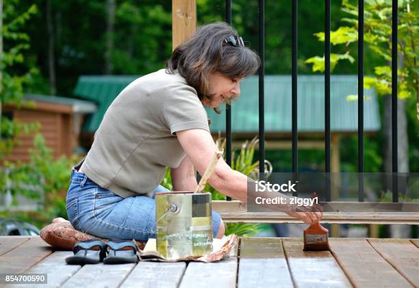 Lifestyle Senior Woman 50 Paints A Deck Stock Photo - Download Image Now - Deck, Wood Stain, Repairing