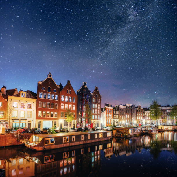 beautiful night in amsterdam. night illumination of buildings and boats near the water in the canal. - amsterdam holland city night imagens e fotografias de stock