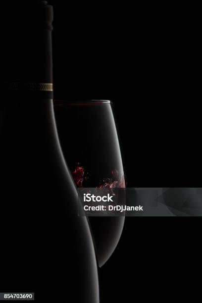 A Bottle And Glass Of Elegant Red Wine With Splash Stock Photo - Download Image Now