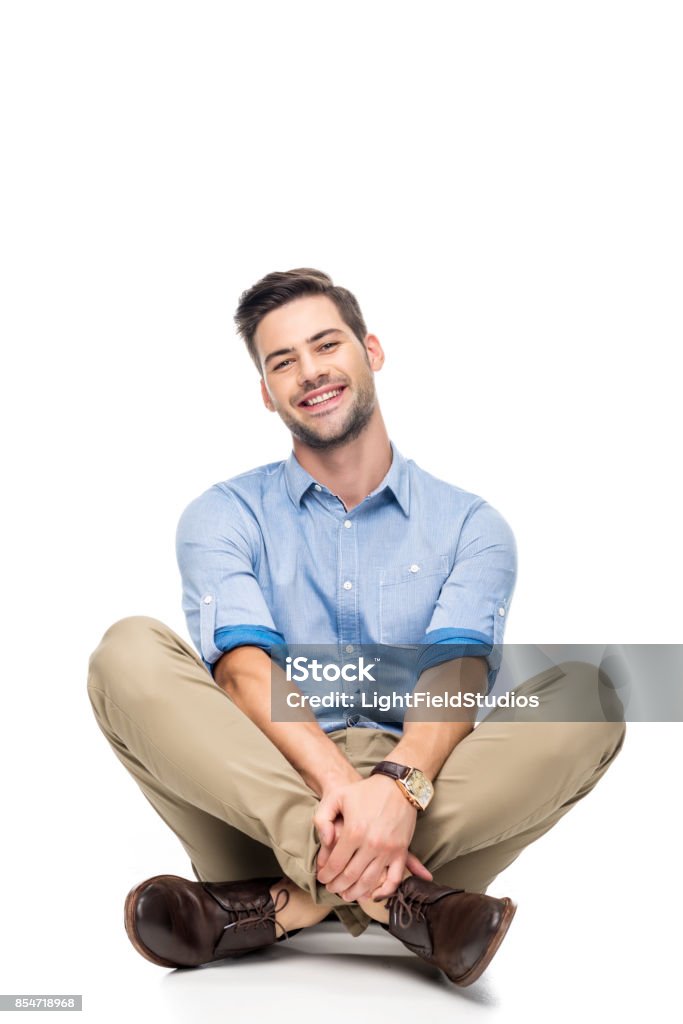 young man sitting on floor happy young man sitting on floor with crossed legs isolated on white Men Stock Photo