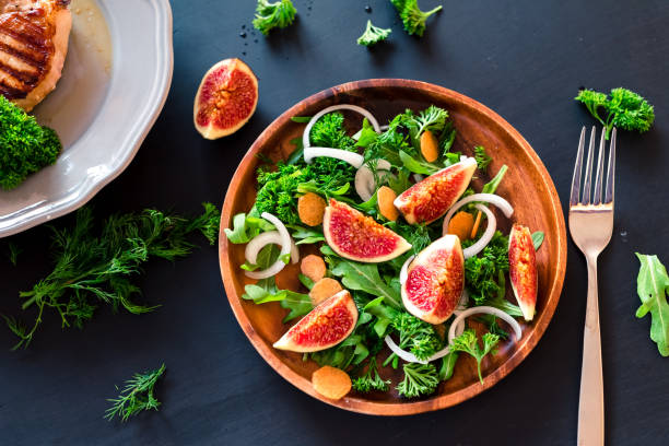 istock Autumn salad of arugula, figs in a brown earthenware plate on a dark background. top view 854724268