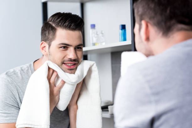 istock man looking at mirror and wiping face with towel 854725558