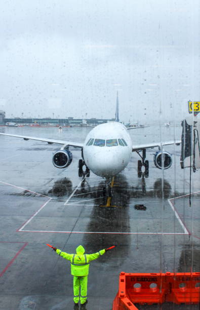 ground crew directing an incoming airplane into position to meet a jet-way bridge. - jet way imagens e fotografias de stock