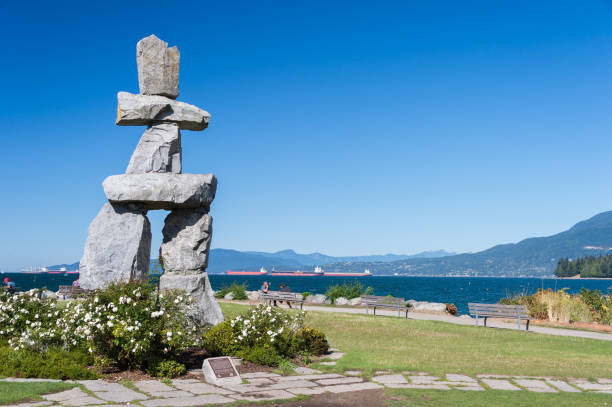 Vancouver, B.C., Canada - 14 September 2017: Inukshuk Monument at English Bay in a public park with people sitting on benches