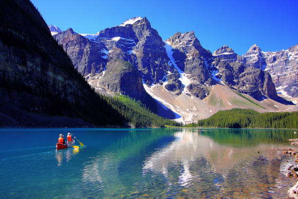 Canoeing on Moraine Lake This was shot at Moraine Lake in July 2009 in the Canadian Rockies near Banf of Alberta, Canada.  The tranquility of the lake and the natural beauty in the region makes it a very popular tourist attraction. moraine lake stock pictures, royalty-free photos & images