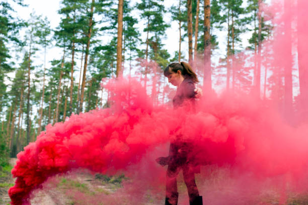 istock Young woman in forest having fun with red smoke grenade, bomb 854862756