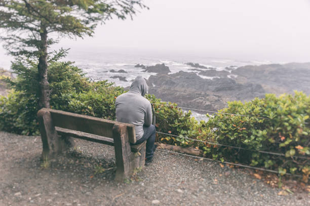 istock Sad and lonely man sitting on bench overlooking sea on Vancouver Island 854862846