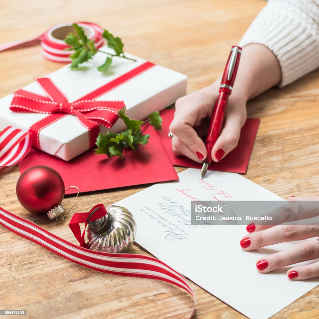 赤い爪、赤いペンと休日の装飾でクリスマス カードを書く若い女性 - クリスマスカードのロイヤリティフリーストックフォト