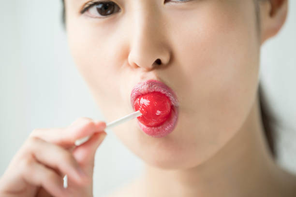 istock A woman is eating a candy with a narrowed mouth. 854885802