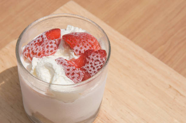 strawberry cream cheese dessert in shot glass on wooden background