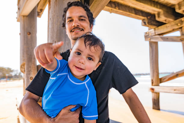 aboriginal australian father and son at the beach - aborigine imagens e fotografias de stock