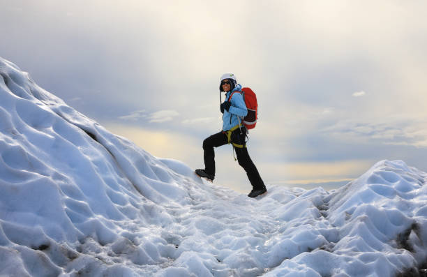 The girl climbing the glacier. Falljokull Glacier (Falling Glacier) in Iceland The girl dressed in a blue jacket and helmet on her head standing on the icy top of Falljokull Glacier (Falling Glacier) in Iceland ice floe photos stock pictures, royalty-free photos & images
