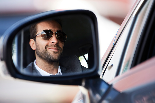 Smiling stubble guy in rear view mirror of car