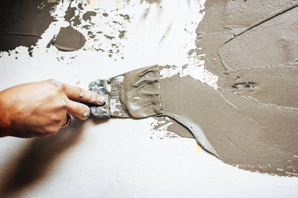 istock Painting worker puttied wall using a paint spatula hand closeup. 854931978