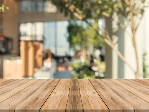 Wooden board empty table top on of blurred background. Perspective brown wood table over blur in coffee shop background - can be used mock up for montage products display or design key visual layout. stock photo