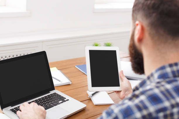 istock Young casual manager working with laptop and tablet in office, close up 854947344