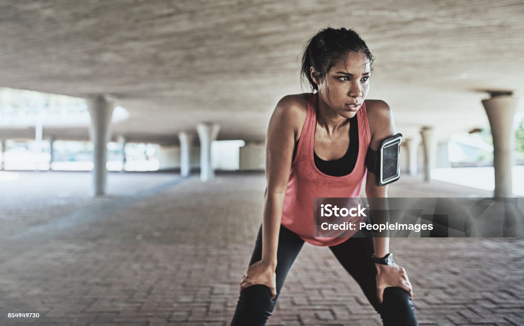 You've gotta sweat for it Shot of a sporty young woman taking a break while exercising outdoors Sweat Stock Photo