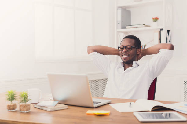 istock Relaxed black businessman with laptop in modern white office 854949786
