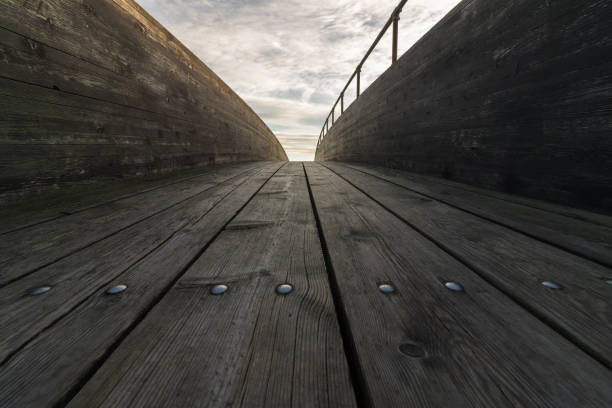 Close view of the planks in a wooden curved bridge with clouds and sky above, Verdens Ende Vestfold, Norway