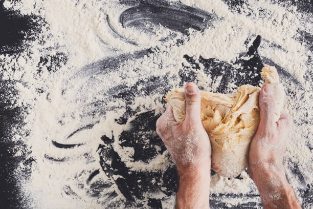 istock Hands top view knead dough on black background 854964860