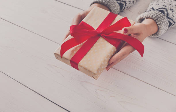 istock Woman's hands give christmas gift in present box 854969456