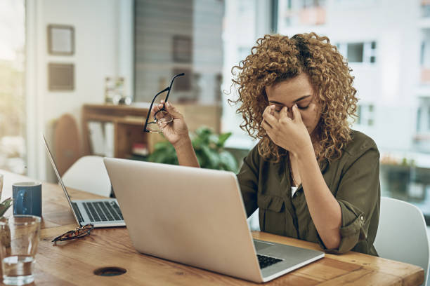 When the road to success leads to stress Shot of a young woman suffering from stress while using a computer at her work desk managing stress stock pictures, royalty-free photos & images