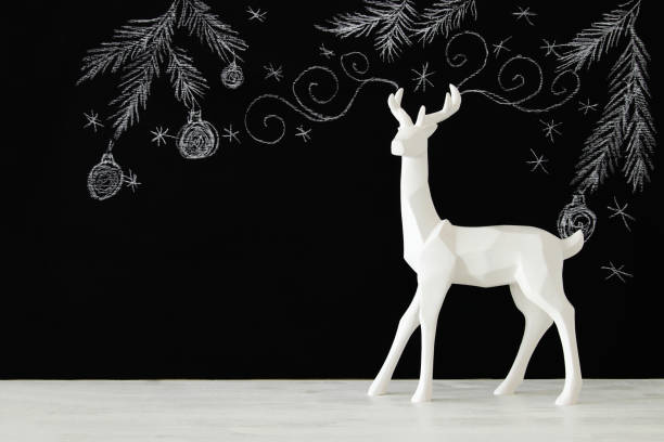 istock White reindeer on wooden table over chalkboard background whith hand drawn chalk illustrations. 854973884
