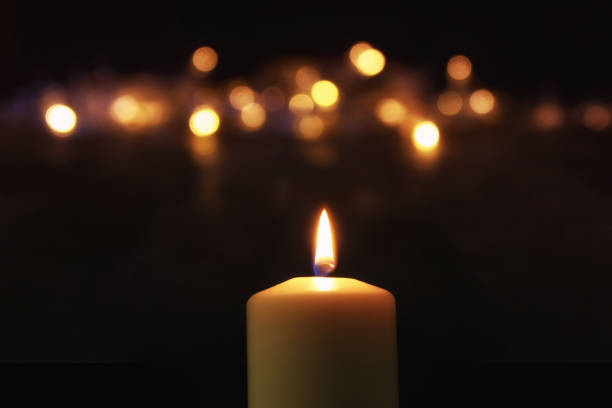 istock Burning candles over black background with bokeh glitter lights 854973964