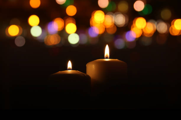 istock Burning candles over black background with bokeh glitter lights 854974050
