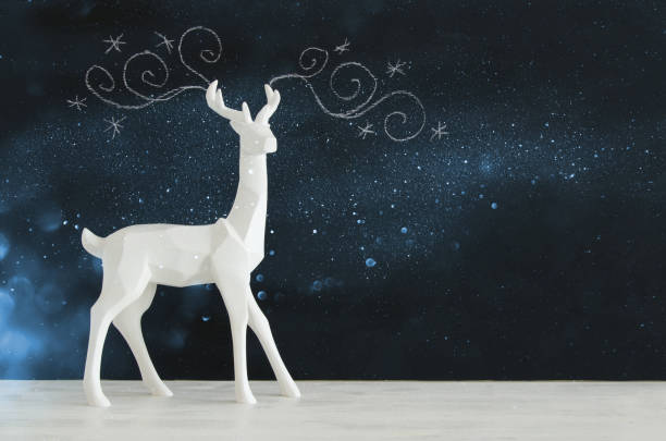 istock White reindeer on wooden table over chalkboard background whith hand drawn chalk illustrations 854980304