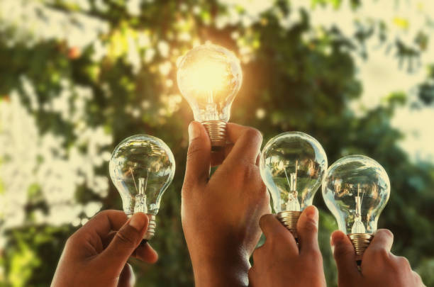 solar energy concept hand group holding light bulb in nature