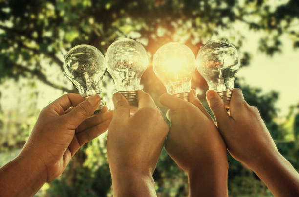 istock solar energy concept hand group holding light bulb in nature 854981212
