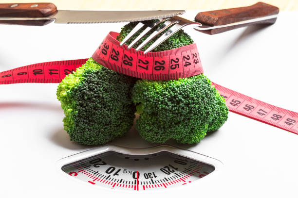 istock Broccoli with measuring tape on weight scale. Dieting 854985176