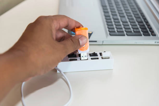 istock hand pushing usb drive into usb slot on laptop.