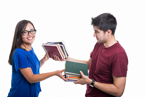 Handsome student couple exchanging bunch of books  isolated on white background
