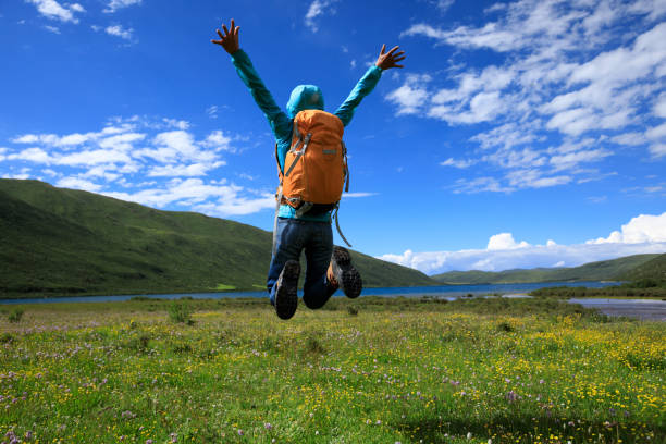 istock cheering young backpacking woman jumping on flowers and grass 854995378