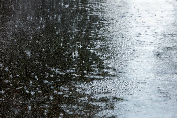 istock wet asphalt sidewalk with falling raindrops and water puddles 854995652