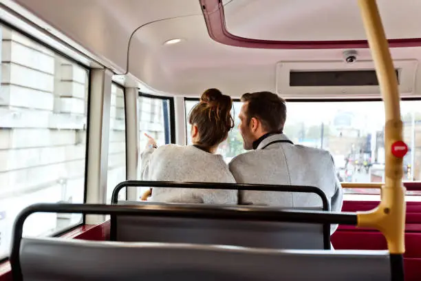 Back view of couple using public transport, sitting in the city bus and sightseeing London.