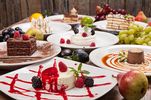 Set of various desserts on a wooden table decorated with fruits and berries.