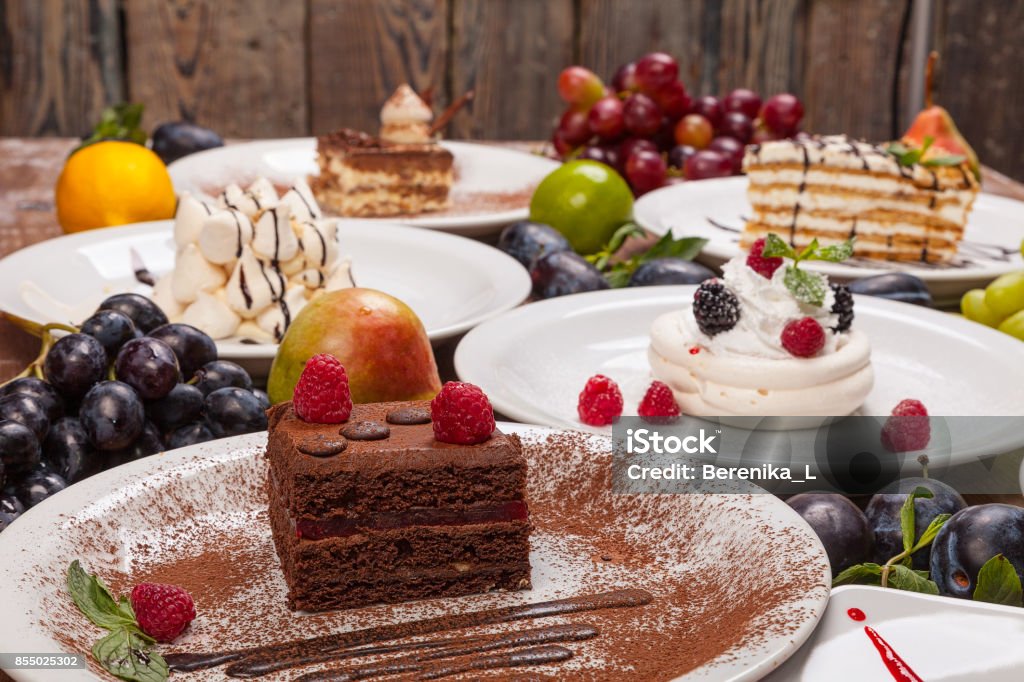 Set di vari dessert su un tavolo di legno decorato con frutta e bacche. - Foto stock royalty-free di Varietà - Concetto