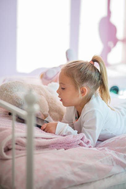 istock Caucasian girl using digital tablet on bed 855026838