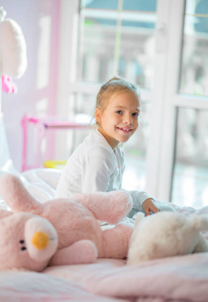 istock Smiling girl siting on bed and looking at camera 855029764