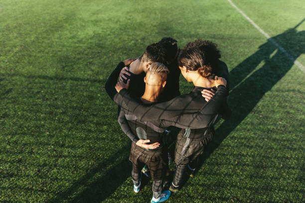 Soccer team standing in a huddle Five a side football team gathering before match. Young soccer team standing in a huddle. softball pitcher stock pictures, royalty-free photos & images