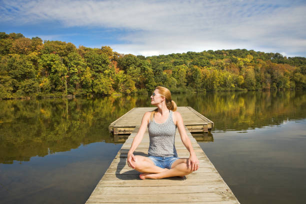 A 45 year old woman sitting on a boat dock enjoying a very warm early fall day.