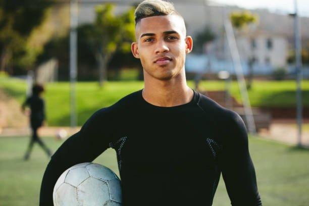 Portrait of teenage soccer player Portrait of teenage soccer player holding a football in his hand and looking at camera. Young man during training on football field. soccer player photos stock pictures, royalty-free photos & images